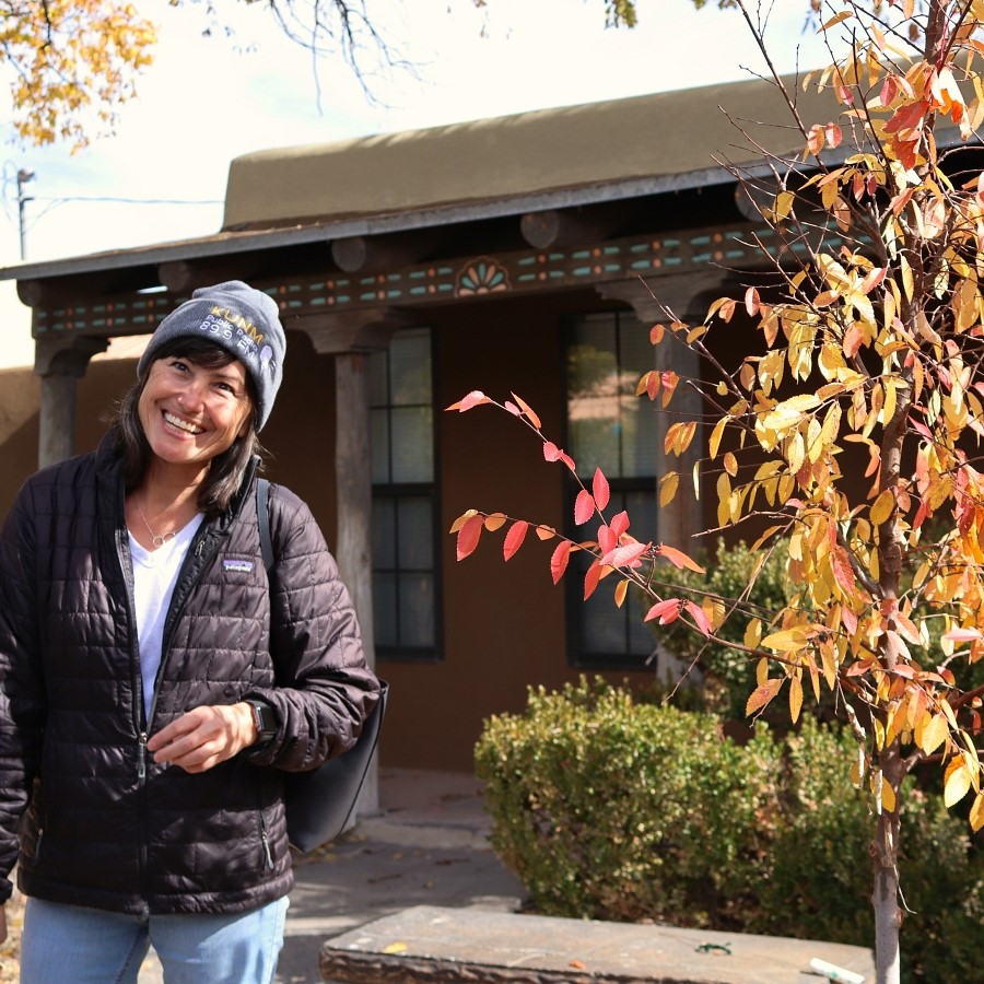 Chanda Shaw, KUNM Development Director, next to an Allee Elm that KUNM helped plant